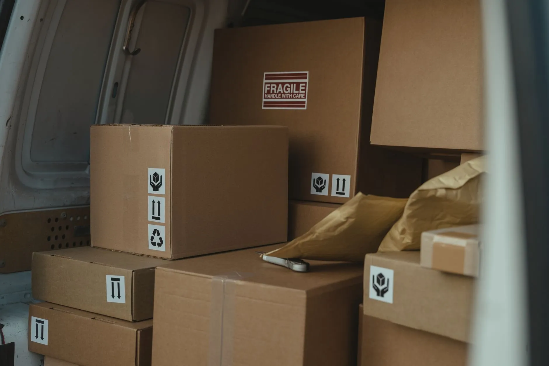 Cardboard boxes with handling labels stacked in the back of a van ready to unload